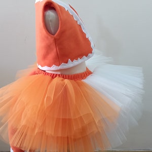 May include: Orange and white fox costume for a baby or toddler. The costume includes a vest, a tulle skirt, and a tail.