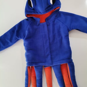 May include: Blue and orange octopus costume for a child. The costume has a hood with large eyes and a zipper closure. The bottom of the costume has eight tentacles.