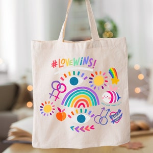 May include: A white canvas tote bag with a rainbow, hearts, and the text "#LOVEWINS!" printed on it. The bag has a colorful design with a rainbow, hearts, and the text "#LOVEWINS!" printed on it.