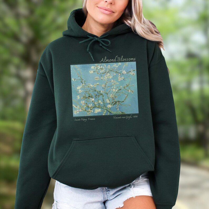 A woman wearing a green hoodie with a graphic of a tree with flowers on it.