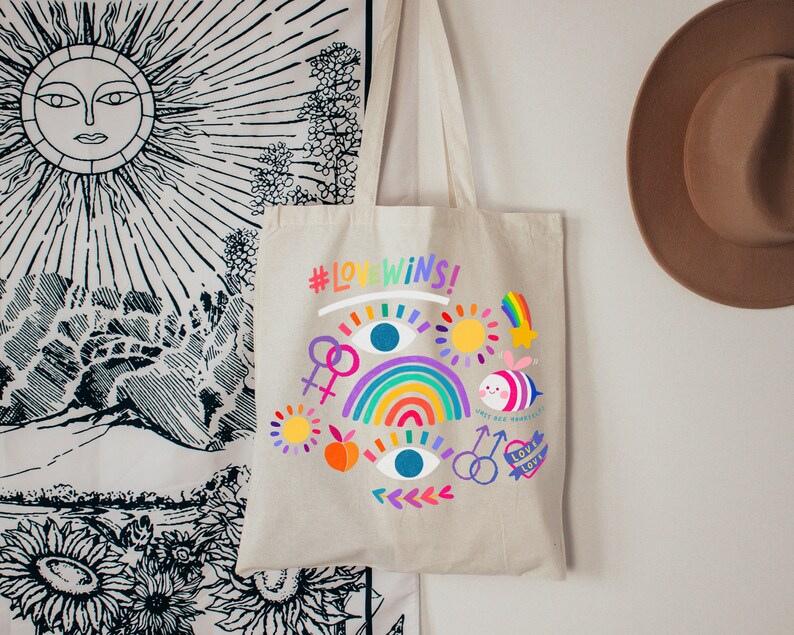 May include: A beige tote bag with a rainbow, eyes, and a bee design. The bag has the text "#LOVEWINS!" printed on it.
