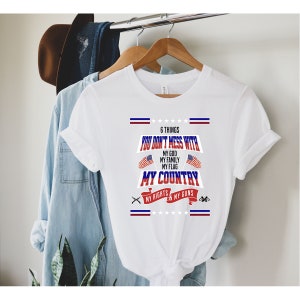 Puede incluir: Camiseta blanca con un diseño gráfico rojo, blanco y azul. El gráfico dice "6 cosas con las que no te metes: Mi Dios, Mi Familia, Mi Bandera, Mi País, Mis Derechos & Mis Armas".