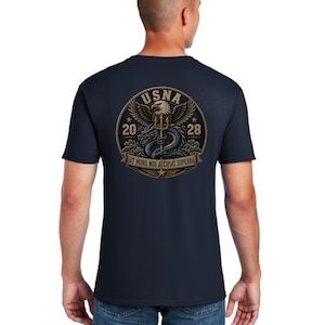 May include: A navy blue short-sleeve t-shirt featuring a circular graphic on the back. The design includes a bald eagle holding a trident above a blue dragon, with the text USNA, 2028, and the Latin phrase UT MORS NOS ACCIPIAT SUPERBA.