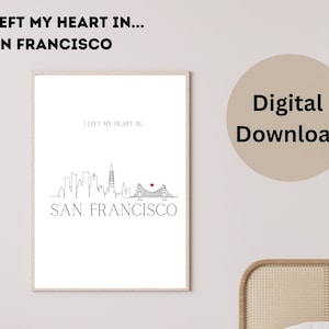 May include: A framed print featuring a minimalist line drawing of the San Francisco skyline, including the Golden Gate Bridge with a heart. The text "I LEFT MY HEART IN... SAN FRANCISCO" is displayed above and below the skyline.
