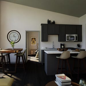 May include: Interior shot of a modern kitchen and dining area. Features include dark gray cabinetry, a stainless steel refrigerator, and a breakfast bar with stools. A wooden dining table with chairs and a large clock are also visible.