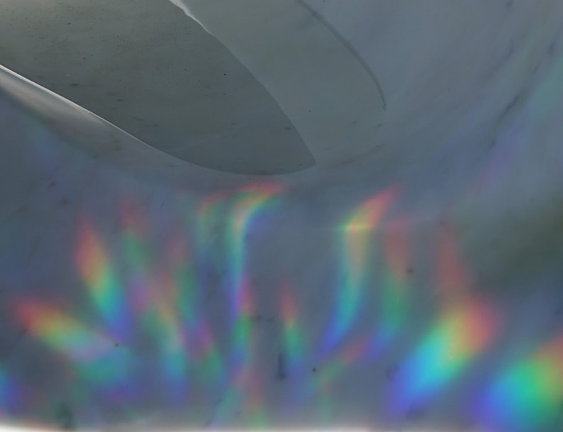 Pu&ograve; includere: Primo piano di una superficie olografica con colori arcobaleno iridescenti che si riflettono su di essa.