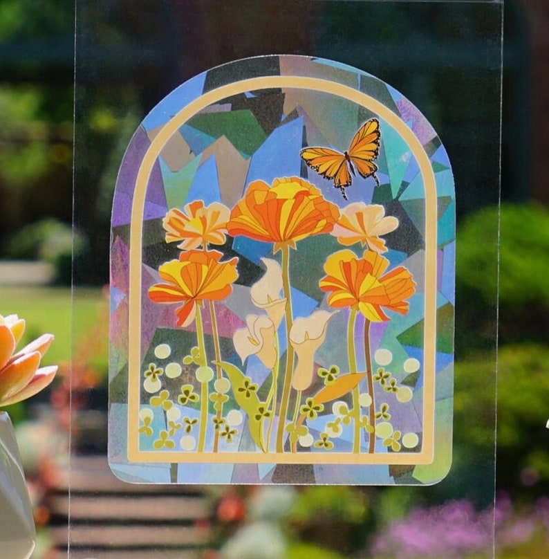 Pu&ograve; includere: Un adesivo per finestre in vetro colorato con una farfalla e fiori arancioni con foglie verdi. L'adesivo &egrave; progettato per assomigliare a una finestra in vetro colorato.