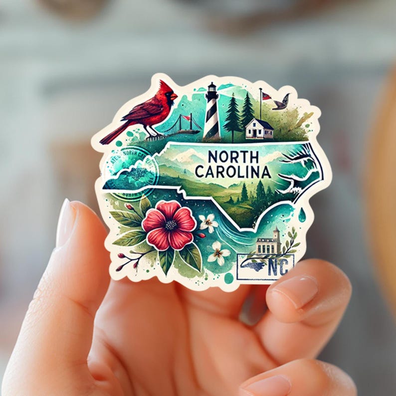 Puede incluir: Una colorida pegatina con la forma de Carolina del Norte, con un cardenal rojo, un faro y el texto "NORTH CAROLINA". La pegatina tambi&eacute;n incluye una flor roja y la abreviatura del estado, "NC".