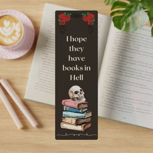 May include: A black bookmark featuring a skull and a stack of books. It reads "I hope they have books in Hell."