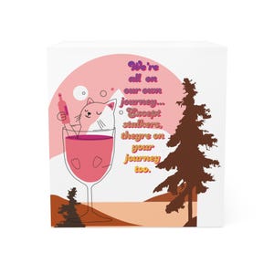May include: A white square block featuring a cartoon design. A pink cat is depicted in a wine glass filled with pink liquid. The image includes a bottle, a tree, and text that reads "We're all on our own journey... Except stalkers, they're on your journey too."