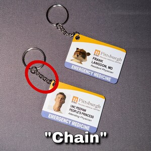 May include: Two keychains with ID cards. The cards have a yellow and white design with the text "Pittsburgh Trauma Medical Center" and "Emergency Medicine". One card features a raccoon image and the other a man's photo.