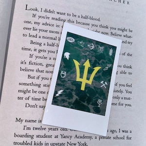 May include: A yellow trident symbol on a green background with various symbols around it. The symbols include a lotus flower, a bird, a bow and arrow, a lyre, a wheat stalk, an owl, a lightning bolt, a pickaxe and a microphone.
