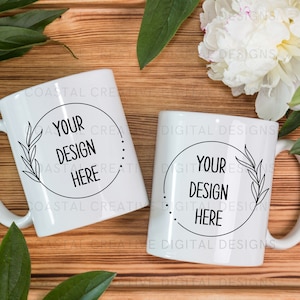 May include: Two white ceramic mugs with black text and a simple leaf design. The text on the mugs reads "Your Design Here".