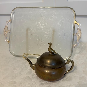 Vintage  brass or copper tea pot with a bird shaped finial on the  lid.