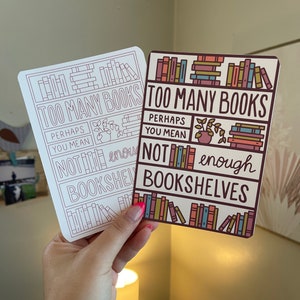 May include: Two cards with a humorous message about books and bookshelves. The top card reads "Too Many Books" and the bottom card reads "Perhaps you mean not enough bookshelves". Both cards feature illustrations of books on shelves.
