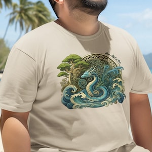 May include: A beige short-sleeved t-shirt featuring a central graphic print of a blue dragon coiled amidst stylised ocean waves and a green tree, all framed within a circular decorative border with intricate knotwork patterns.