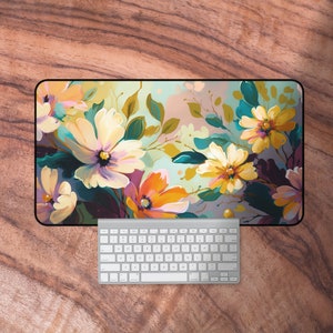 May include: A floral design desk mat with a white background and colourful flowers in shades of yellow, orange, purple, and teal.