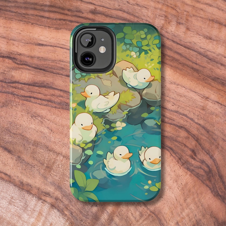 May include: A phone case with a colorful illustration of five white ducks swimming in a pond with green foliage and rocks. The case has a camera cutout and a black border.