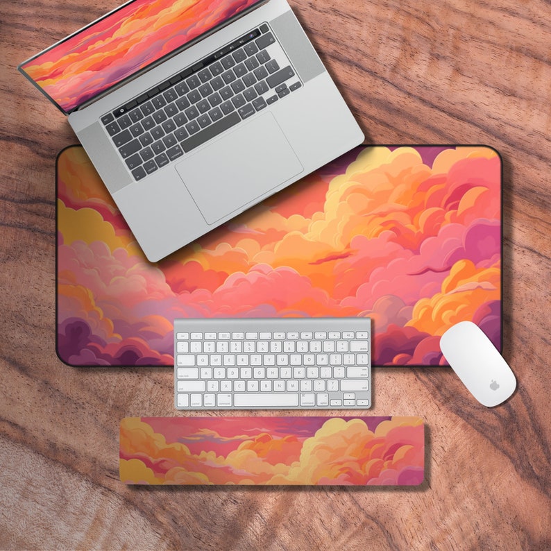 Puede incluir: Una configuraci&oacute;n de escritorio con una computadora port&aacute;til, teclado, rat&oacute;n y una alfombrilla de escritorio con un dise&ntilde;o de nubes coloridas. La alfombrilla de escritorio es de color rosa claro, naranja y amarillo con un contorno morado oscuro.