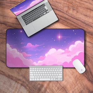 Peut inclure: Un tapis de bureau violet et rose avec une illustration de dessin animé d'un ciel nocturne avec des nuages et des étoiles. Un ordinateur portable, un clavier et une souris sont sur le tapis de bureau.