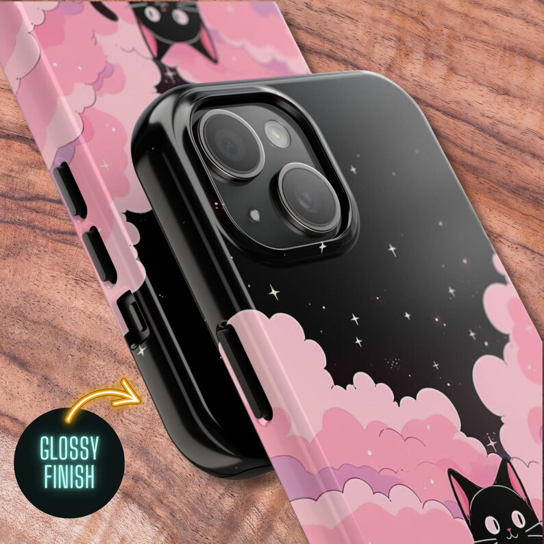 May include: A black phone case with a pink and black design featuring clouds and a black cat. The case has a glossy finish.