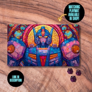 May include: A rectangular playmat featuring a stained-glass style illustration of a robot with blue, purple, orange, and yellow hues. The playmat has the text "LINK IN DESCRIPTION" and "MATCHING PLAYMAT AVAILABLE IN SHOP!" on it. Three purple dice are also visible.