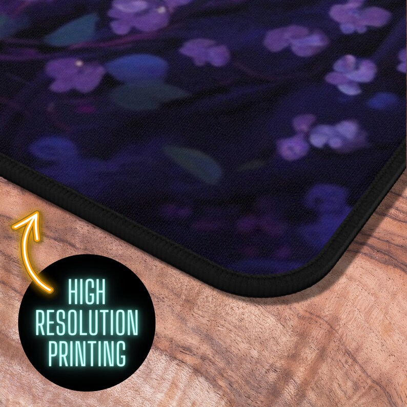 May include: A black mousepad with a dark purple floral design. The mousepad has a black stitched edge and is shown on a wooden surface.