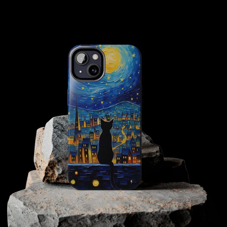 May include: A black cat silhouette sits on a rooftop overlooking a city skyline painted in a starry night style. The phone case features a blue and yellow background with a crescent moon and stars.