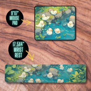 May include: A set of two mouse pads and wrist rests featuring a whimsical illustration of white ducks swimming in a blue stream. The smaller mouse pad is 9 inches by 7 inches, and the larger wrist rest is 17.5 inches by 4 inches.
