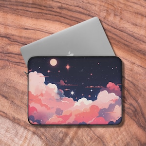 Op de afbeelding: Een laptophuls met een roze en blauwe sterrenhemel ontwerp. De hoes heeft een donkerblauwe achtergrond met roze en witte wolken, een halve maan en sterren.
