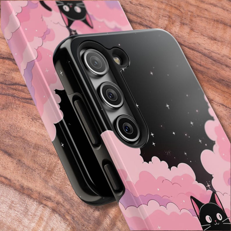 May include: Black phone case with a pink and purple cloud design and black cats. The case has a black camera bump with three lenses.