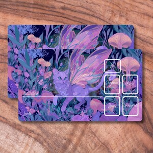 May include: Two rectangular playmats featuring a fantasy illustration. The design includes a purple cat with fairy wings, mushrooms, and foliage in shades of purple, blue, and green. Text includes "Battlefield" and other game-related terms.