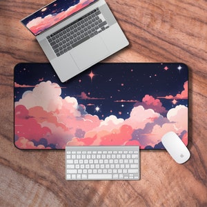 May include: A desk mat with a dark blue background and a pink and white cloud design. The mat is decorated with white stars and has a laptop, keyboard, and mouse on top of it.