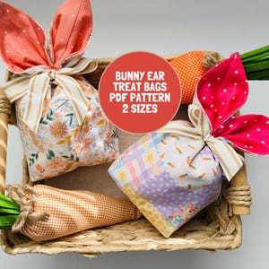 May include: Two fabric treat bags with bunny ear closures and beige striped ribbons. One bag features a floral print, the other a checkered pattern with small carrots. A red circular graphic displays the text BUNNY EAR TREAT BAGS PDF PATTERN 2 SIZES.