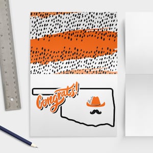 May include: Orange and black congratulations card with a stylized outline of the state of Oklahoma and the word "Congrats!" in a handwritten font. A cowboy hat with the word "Sooners" is on top of the state outline.