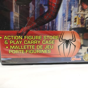 May include: A red and blue Spider-Man action figure store and play carry case with a red and black Spider-Man logo. The text on the case reads "Action Figure Store & Play Carry Case" and "Mallette de Jeu Porte-Figurines".