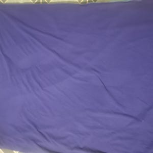 Puede incluir: Una s&aacute;bana morada oscura lisa con pliegues y arrugas visibles. La tela parece suave y tiene un acabado mate. La s&aacute;bana rectangular llena el marco, lo que sugiere un tama&ntilde;o de cama est&aacute;ndar.