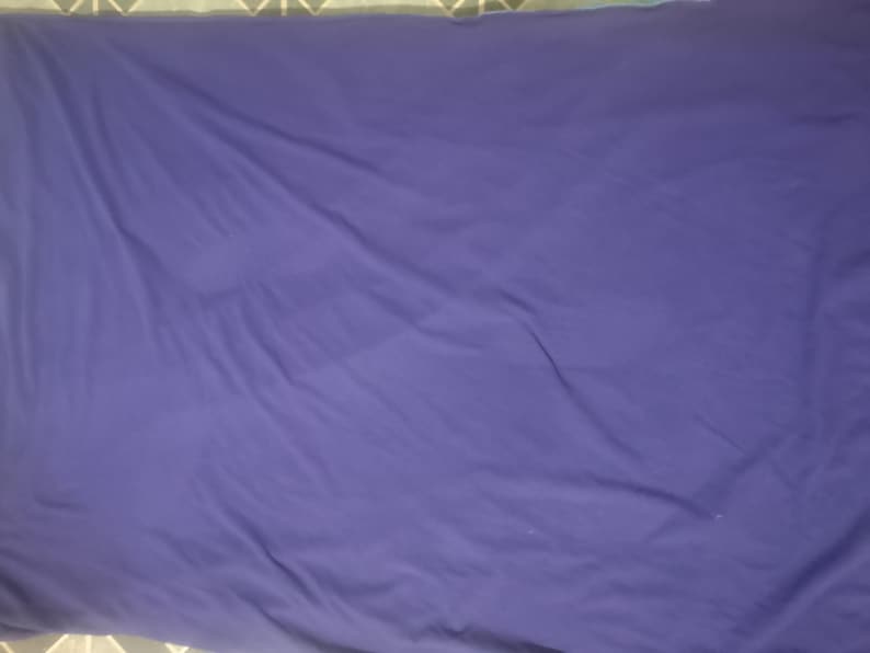 Puede incluir: Una s&aacute;bana morada oscura lisa con pliegues y arrugas visibles. La tela parece suave y tiene un acabado mate. La s&aacute;bana rectangular llena el marco, lo que sugiere un tama&ntilde;o de cama est&aacute;ndar.