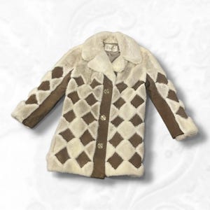 May include: A vintage cream coat with a diamond pattern in brown and cream. The coat has a faux fur collar and trim, with brown suede-like panels on the sleeves and front. It features gold-coloured buttons.