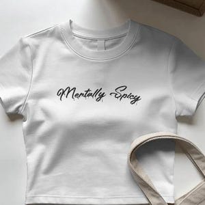 May include: A white short-sleeved crop top featuring the text Mentally Spicy printed in a black, dripping-style script font across the center of the chest. The garment has a crew neckline and a straight hemline, showcasing a clean, simple design.