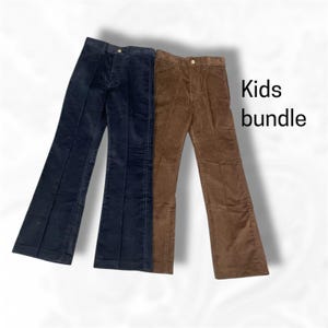 May include: Two pairs of corduroy pants in navy blue and brown. The pants have a flared leg design and button closures. The text "Kids bundle" is displayed in black font.