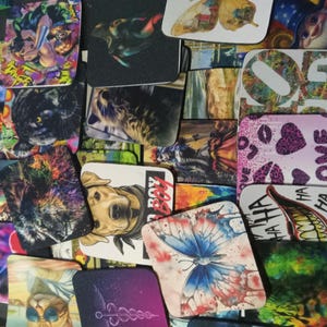 May include: A collection of colorful coasters with various designs, including a black panther, a butterfly, a dog, and a heart with the word "love".