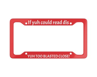May include: Red plastic license plate frame with white text that reads "If yuh could read dis... YUH TOO BLASTED CLOSE!"