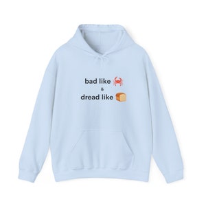 Puede incluir: Sudadera con capucha azul claro con el texto "bad like" y un emoji de cangrejo, seguido de "&" y el texto "dread like" y un emoji de pan.