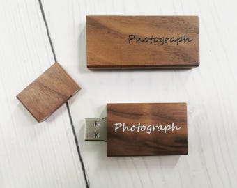 May include: Two rectangular wooden USB flash drives with dark brown wood grain. One drive is closed with a cap, and the other is open with the metal connector exposed. Both feature the word Photograph engraved or printed on the surface.