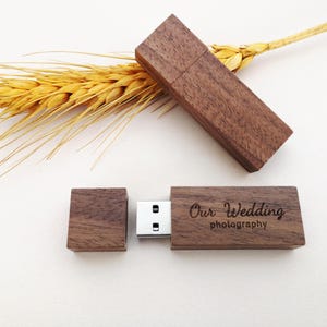 May include: Wooden USB flash drive with the text "Our Wedding photography" engraved on the side. The flash drive is brown and has a rectangular shape. A separate wooden cap is next to the flash drive. A sprig of wheat is in the background.