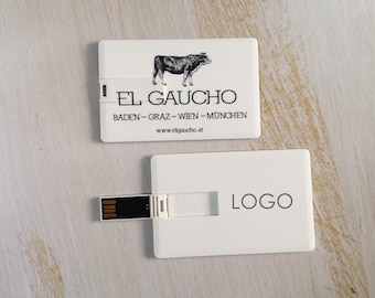 May include: Two white USB flash drives. One has a black and white illustration of a bull and the text "EL GAUCHO" and website address. The other has the word "LOGO" printed on it.
