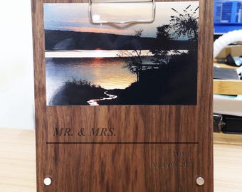 May include: A wooden photo clipboard with a sunset landscape photo. The clipboard has a silver clip at the top and the words "MR. & MRS." and "TOME March 08, 2025" printed on the wood.