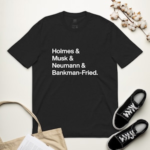 May include: Black t-shirt with white text that reads "Holmes & Musk & Neumann & Bankman-Fried."