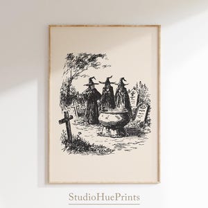 May include: Black and white vintage-style print featuring three witches in cloaks and hats gathered around a cauldron in a graveyard. A cross and tombstones are in the background. The text "StudioHuePrints" is at the bottom.